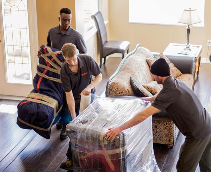 Movers carefully blanket wrapping furniture to protect it during a move.