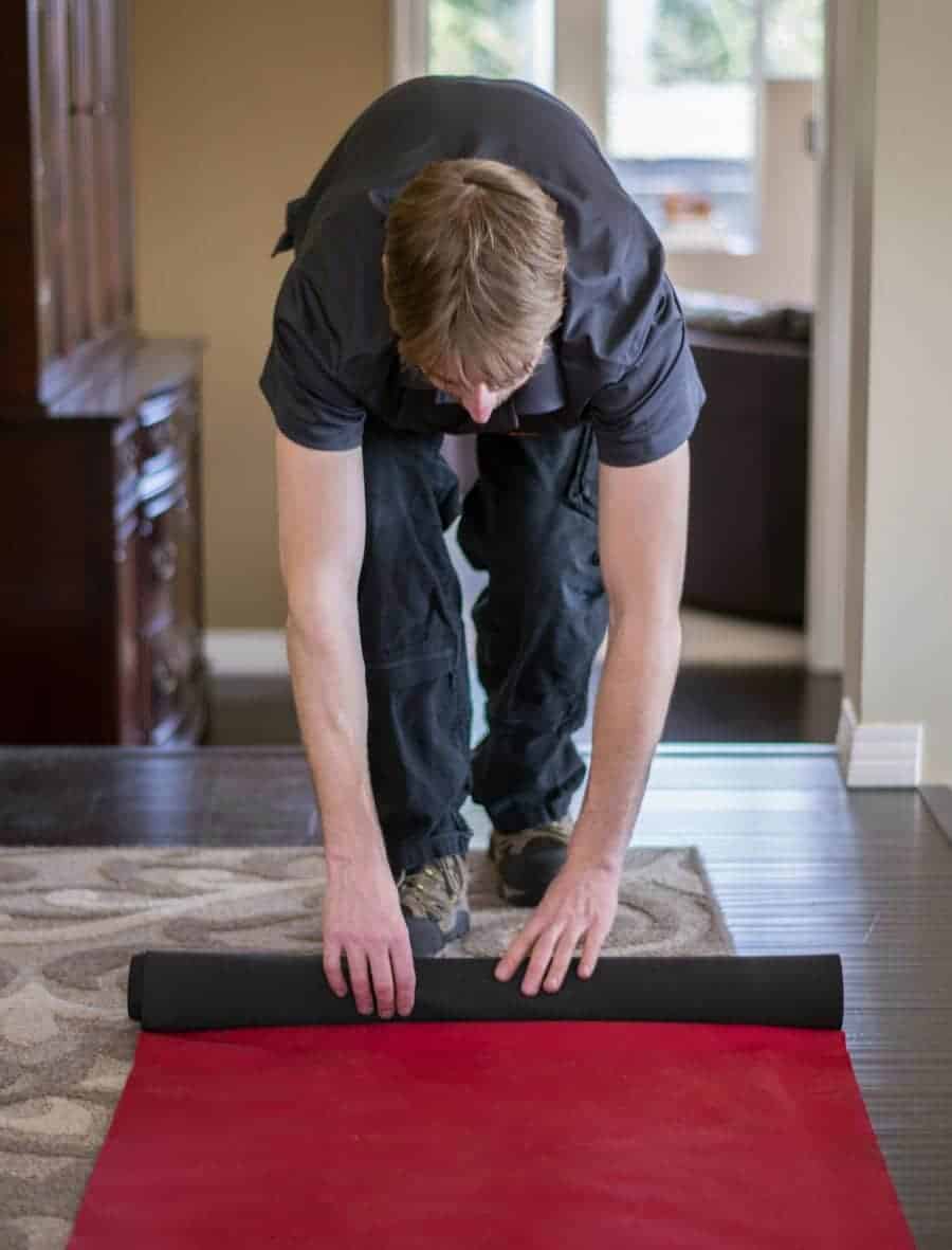Mover rolling out a red floor runner to protect flooring during a move.