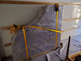 Wrapped piano secured on its side, ready for safe transport during a piano move.