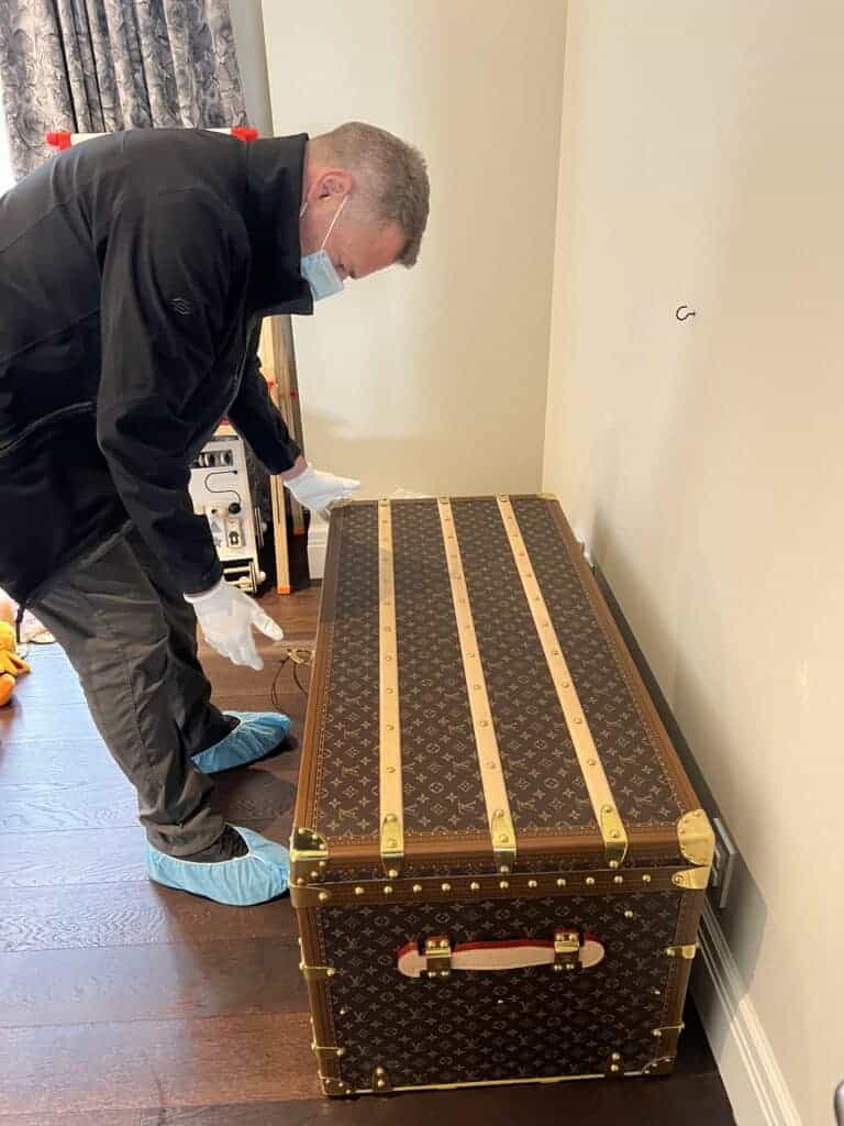 Mover wearing gloves and a mask while preparing to pack an antique box with care.