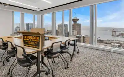 Office space with open windows overlooking city skyline and a moving box on the table, illustrating office moving services.