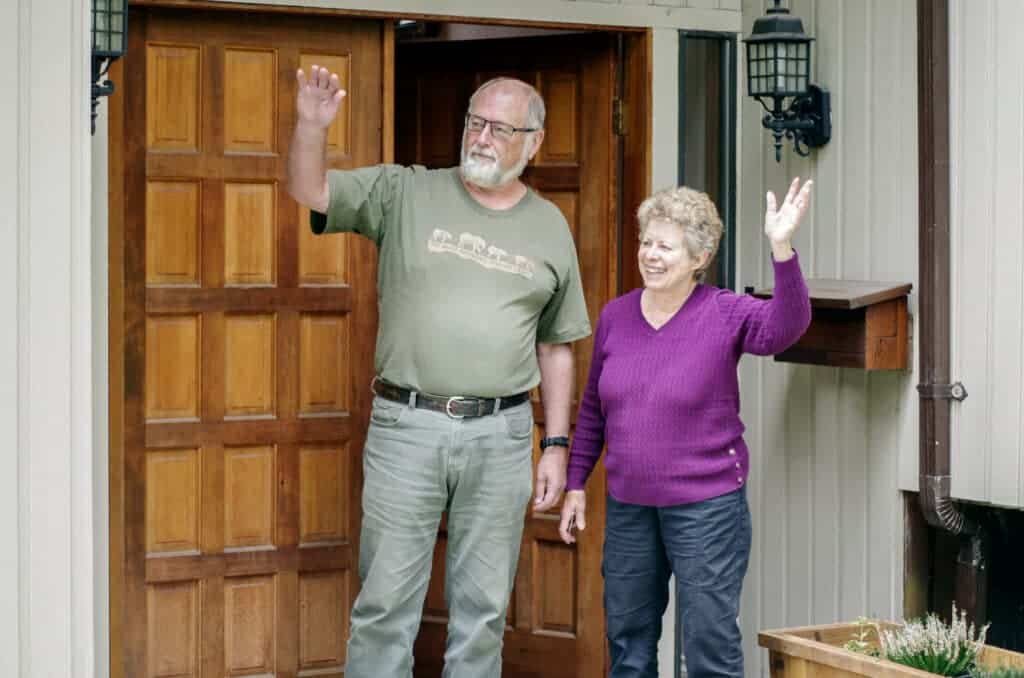 Elderly couple waving goodbye after a moving consultation.