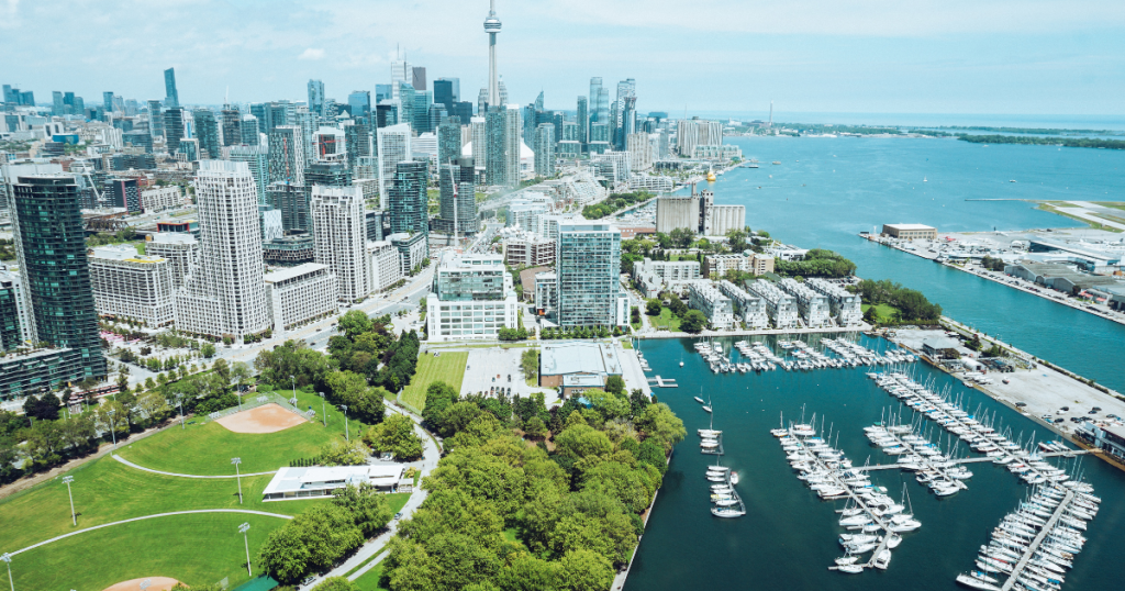 Wide shot of Toronto cityscape with a park and water in the foreground on a clear day.