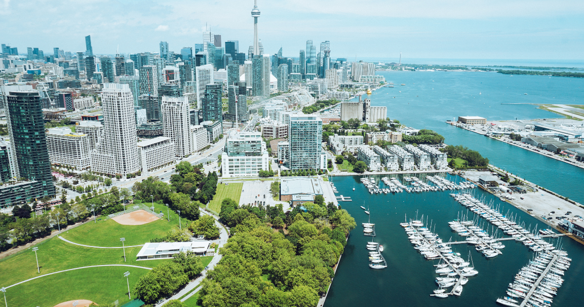 Wide shot of Toronto cityscape with a park and water in the foreground on a clear day.