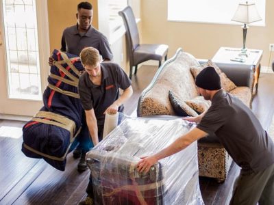 Movers carefully blanket wrapping furniture to protect it during a move.