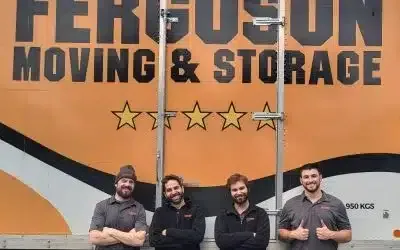 victoria-team- Four local movers smiling in front of a moving truck during a team photo shoot.